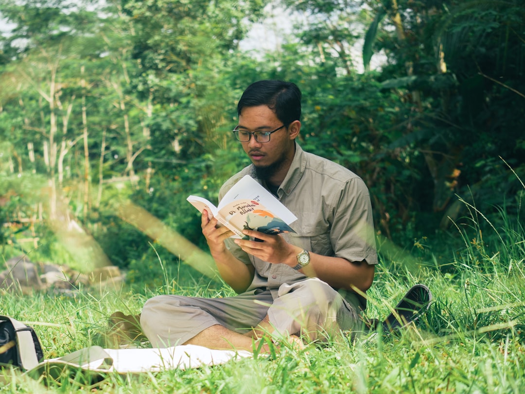 Young man reading book near river